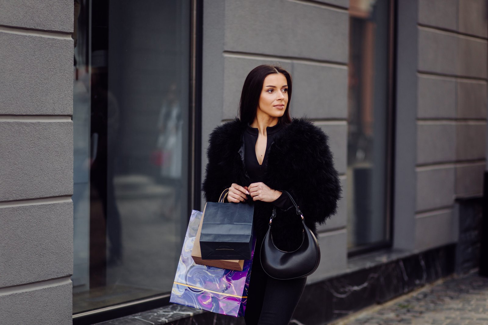 brown-haired-woman-wearing-black-wear-holds-colourful-patterned-shopping-bags-successful-shopping-spree-walking-outside-she-is-enjoying-warmth-day-scaled.jpg